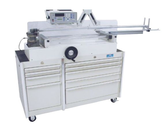 An industrial machine with a control panel and a large work surface mounted on a cabinet with multiple drawers. The setup includes levers, buttons, and a hand crank. The entire unit is on wheels for mobility.