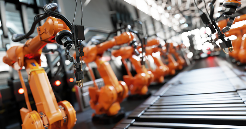 A factory assembly line with multiple robotic arms in operation. The robotic arms are orange and aligned in a row, each equipped with tools for manufacturing tasks. The setting is industrial, with a focus on automation and efficiency.