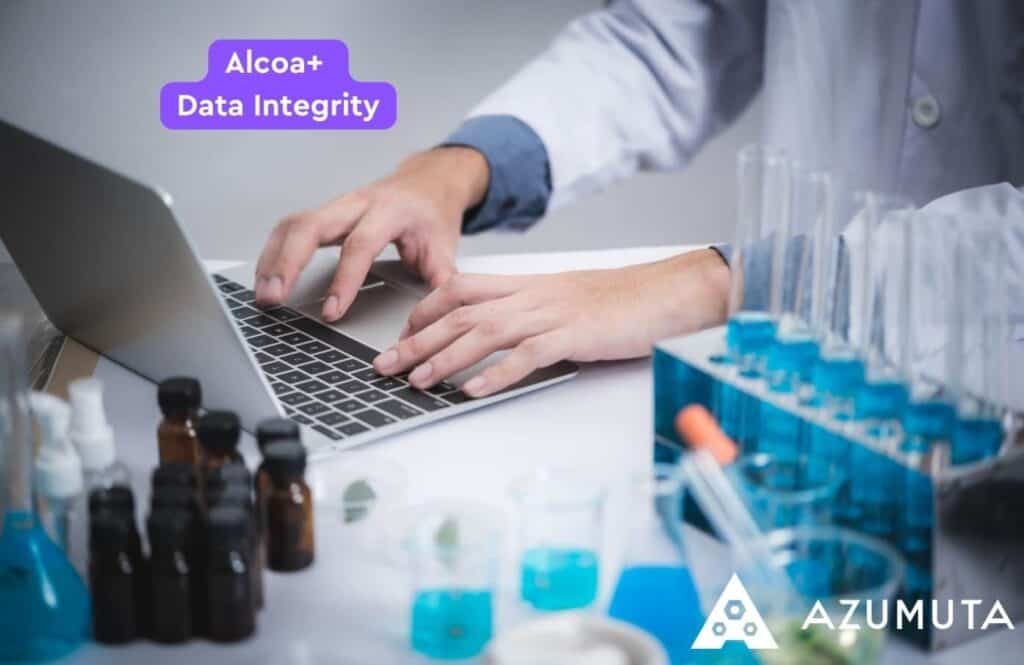 A person wearing a lab coat uses a laptop at a lab table with various scientific supplies, including test tubes, beakers, and vials. The text "Alcoa+ Data Integrity" and "Azumuta" is visible in the image.