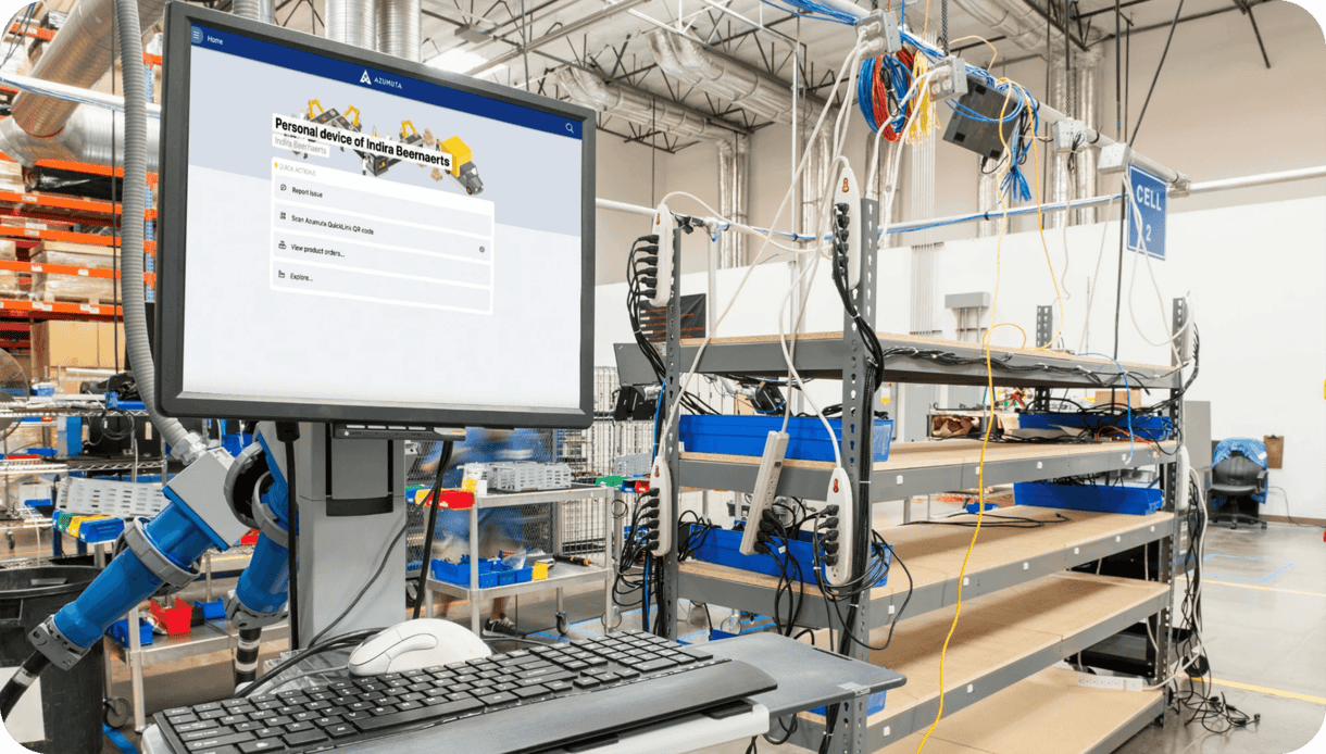 A factory floor featuring a workstation with a desktop computer displaying a survey titled 