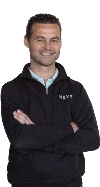 A smiling man with short hair, wearing a black sweater with the text 