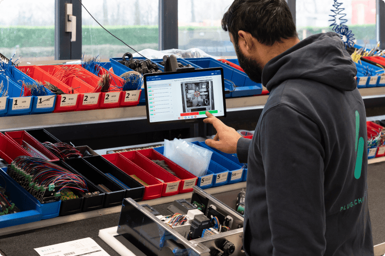 Image showing an operator at the assembly station using a tablet. On the tablet a work instruction is shown. This highlights how the operator can easily follow the different assembly steps.
