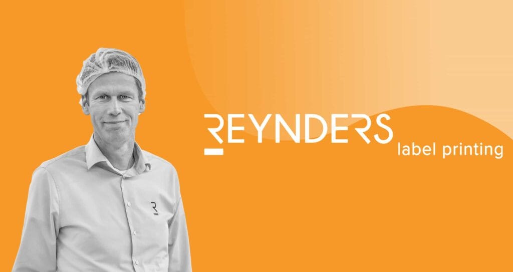 A man wearing a hairnet and a logo-emblazoned shirt is standing against an orange background with the text, "REYNDERS label printing" displayed prominently beside him.